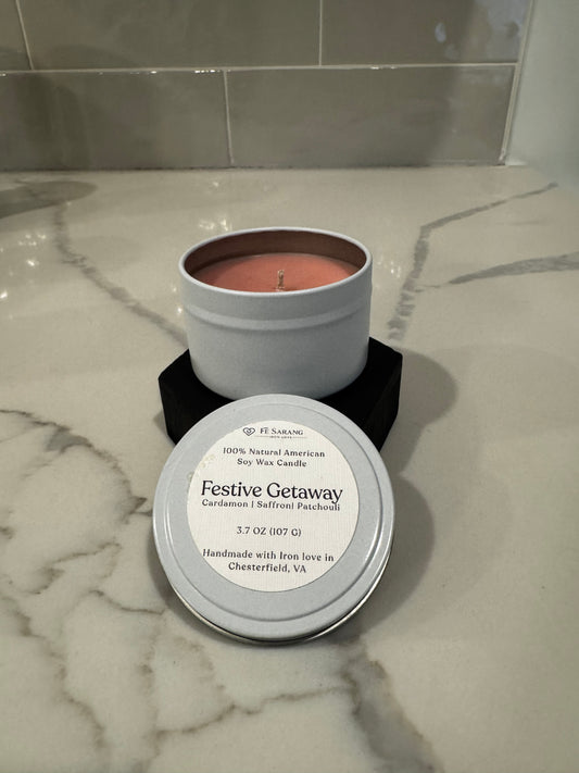 Candle in a metal container with a label on a marble surface