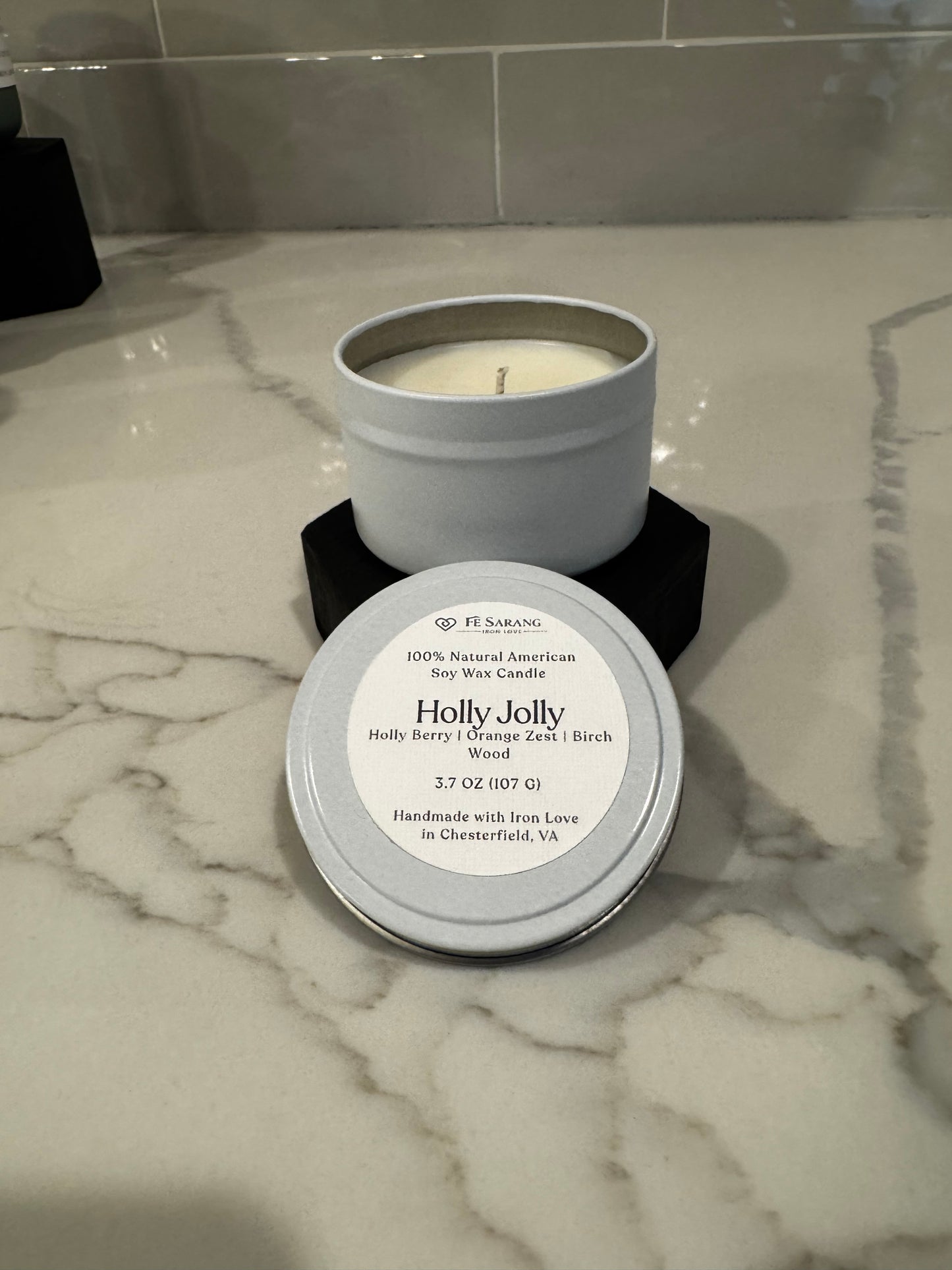 Candle in a tin with a label on a marble surface